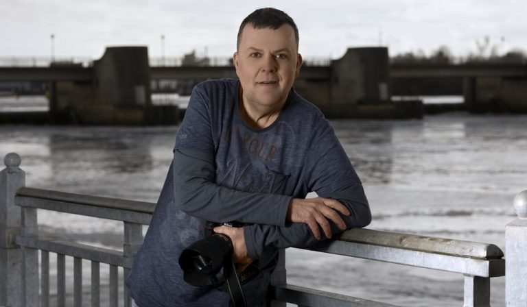 Ein Foto von meinem letzten Personal-Branding Shooting in Bremen – Querformat mit meiner Lieblings-Jeans mit CAMP DAVID Longshirt – leger die Kamera in der Hand und auf einem Geländer am Weserwehr angelegt! Strahlkraft vor der Kamera à la Thomas Schoo.