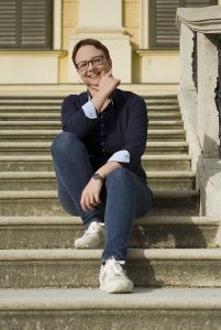 Ein Foto von Anna Zofia Kaltner bei ihrem Personal Branding Shooting Herbst 2023 – sehr entspannt mit ihrem legendären dunkelblauen Hemd – auf den Stufen vor dem Schloss Schönbrunn