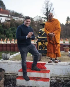 Mit Calvin Hollywood war Sascha Übler auf einer besonderen Mission! Darum trägt er auch etwas feinere Garderobe, Hemd mit Pullover und Jeans mit betender Symbolik. Im Hintergrund ist ein Mönch aus dem Orden zu sehen, der Calvin durch familiäre Bande bekannt ist!