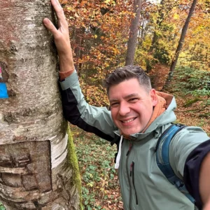 Sascha Übler von Sascha Übler Versicherungen bei einer Wander-Tour im mittelfränkischen Obermichelbach! Er hat dieses Selfie selbst fotografiert und lehnt dabei an einer Birke. Er trägt Tracking-Kleidung und einen Rucksack.