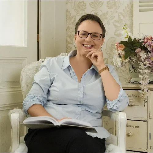 Buchbegleiterin und Mentorin Anna Zofia Kaltner lächelt in einem Sessel mit einem Buch im Schoß – fotografiert von Personal Branding Fotograf Thomas Schoo in Wien.